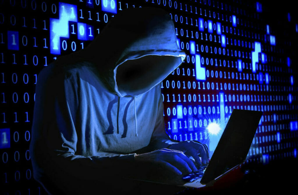 hooded hacker at a laptop