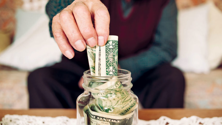 Closeup of older person putting money in jar
