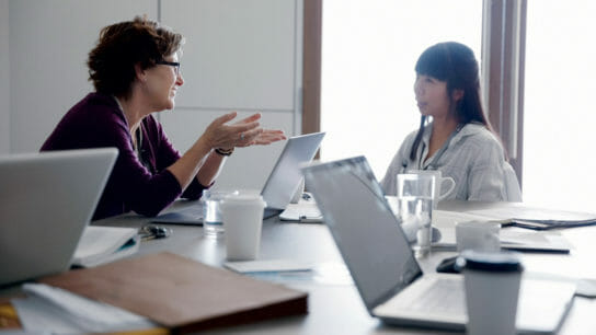 two people sitting at a conference table, talking