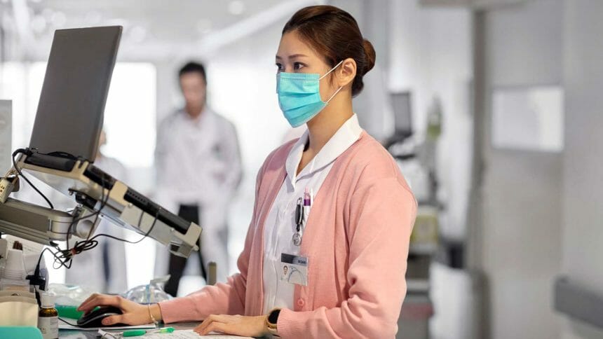 woman nurse wearing face mask and working at computer