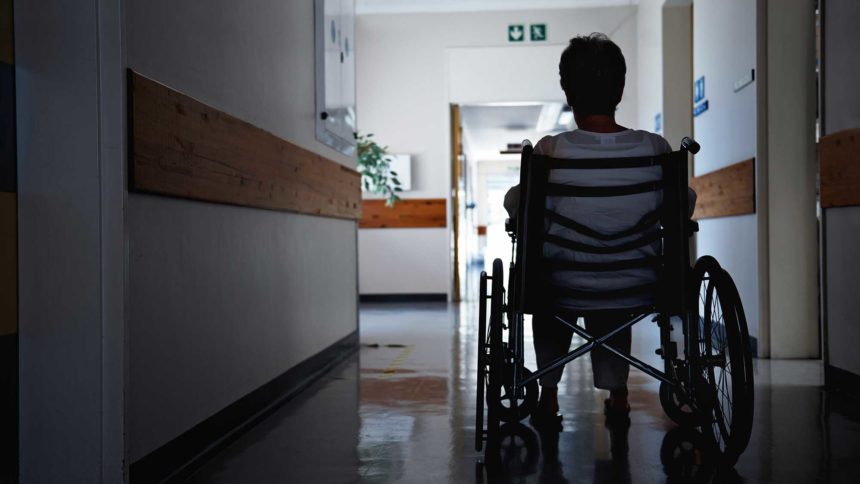 woman in wheelchair sitting in empty, dark hallway