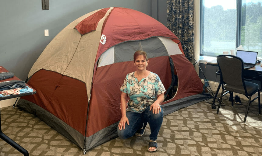 woman kneeling in front of tent set up inside retirement community