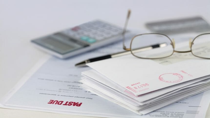 Stack of envelopes with pen, calculator, glasses and credit card
