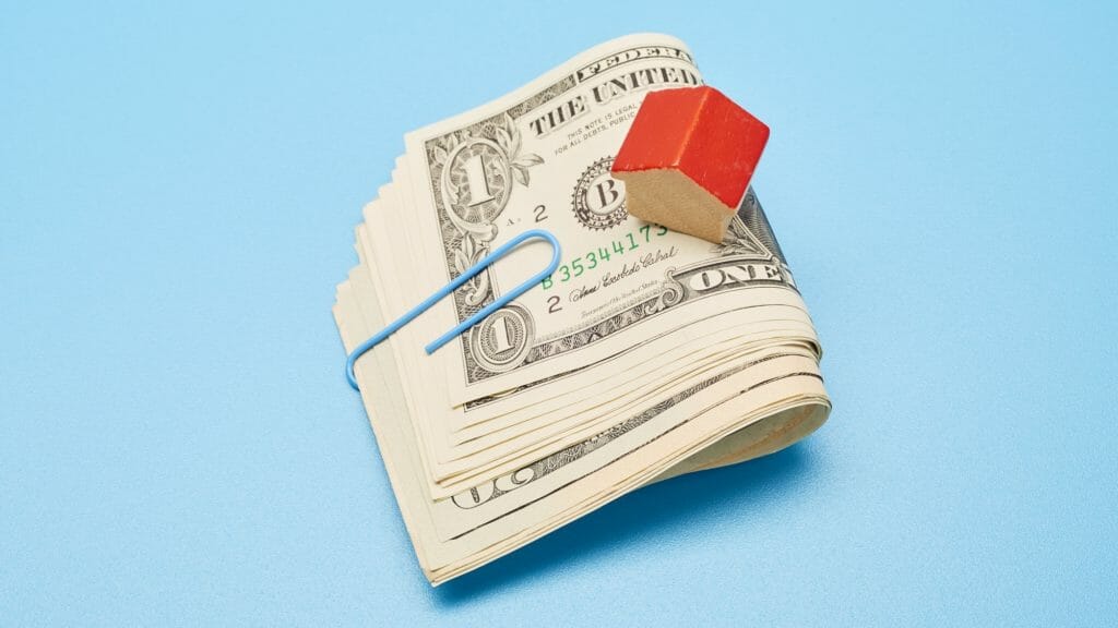 tiny house on top of paperclipped money