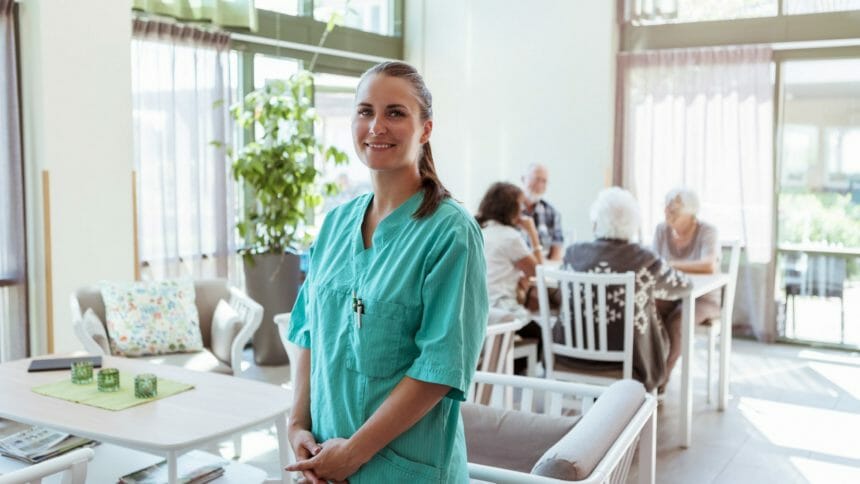 Nurse with table of older adults in background at kitchen table