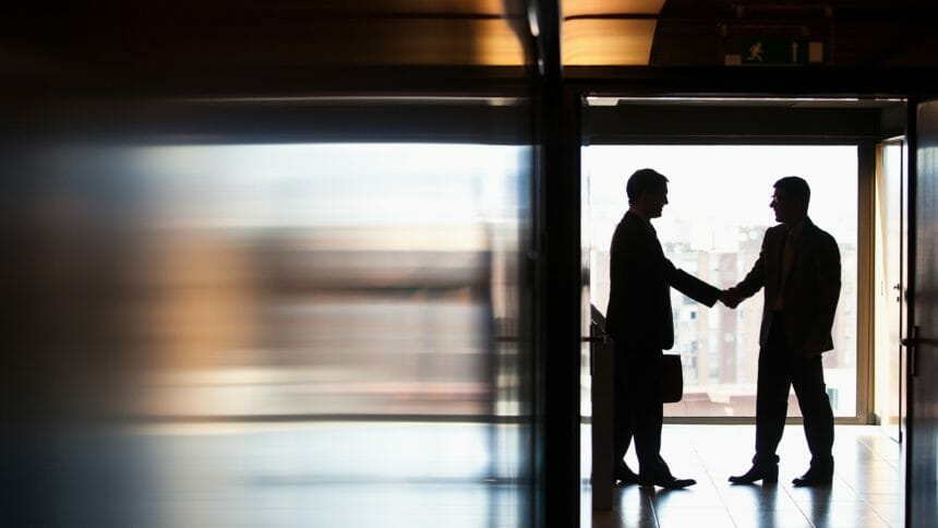 Businessmen shaking hands in corridor