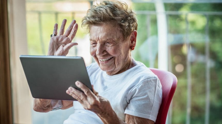 Senior woman using digital tablet on apartment balcony