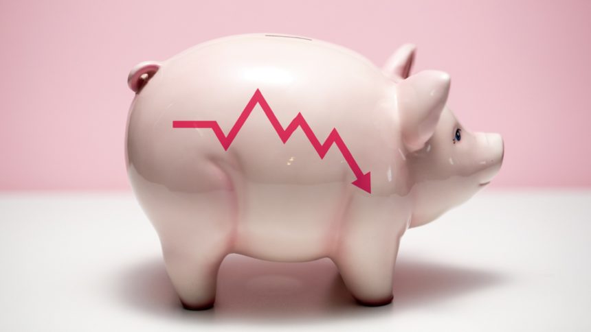 Pink ceramic piggy bank with red line graph showing downward trend, white surface, pink background