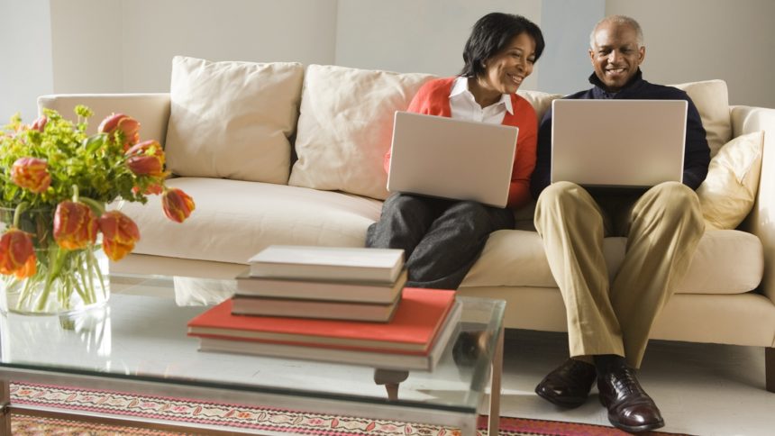 older couple on laptops on the couch