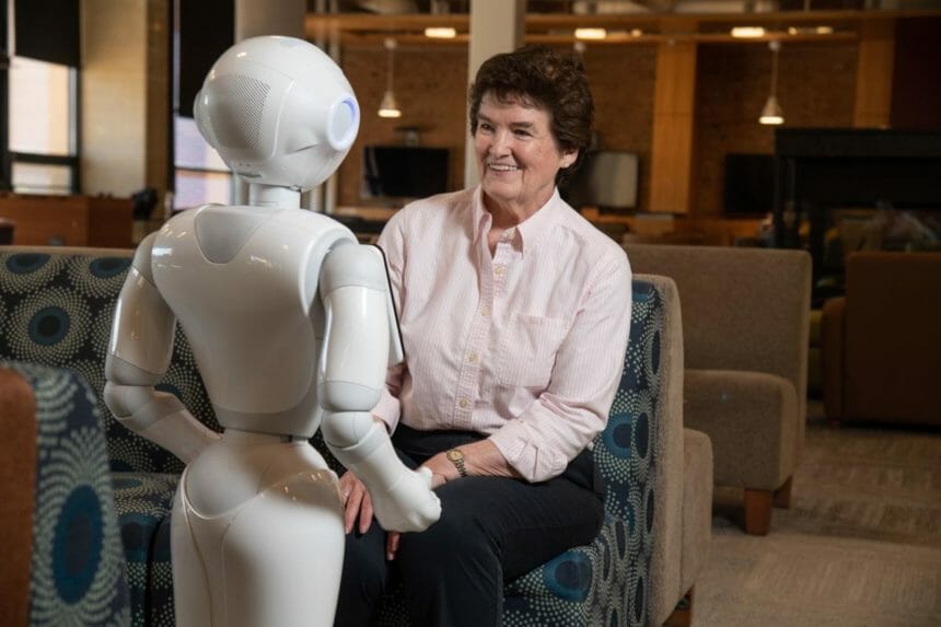 Pepper the robot talking to a woman in a chair.
