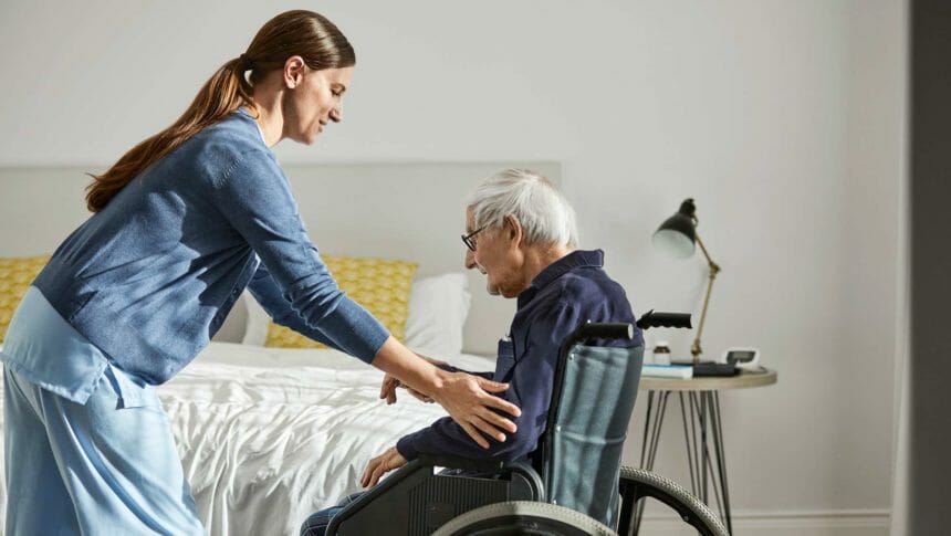 a healthcare worker helping an older adult get out of or into a wheelchair