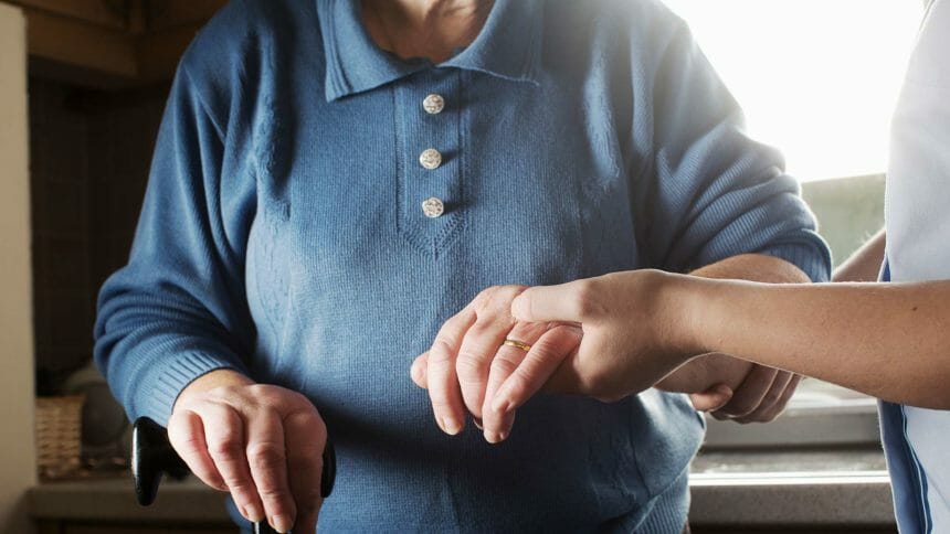 a worker holding an older adult's hand