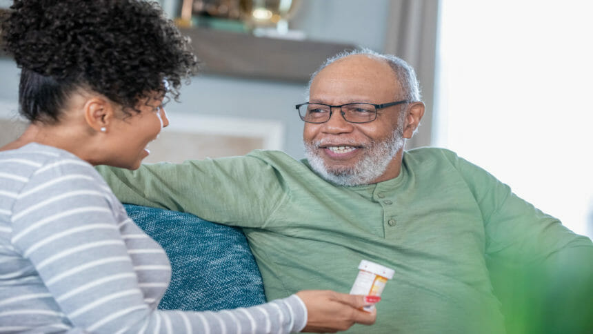 Woman on couch holding pill bottle has conversation with loved one