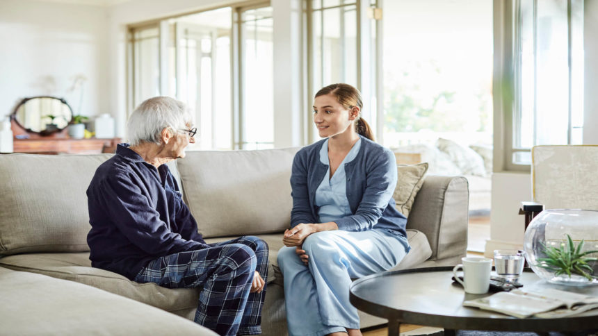 Caregiver talks to patient on couch at home