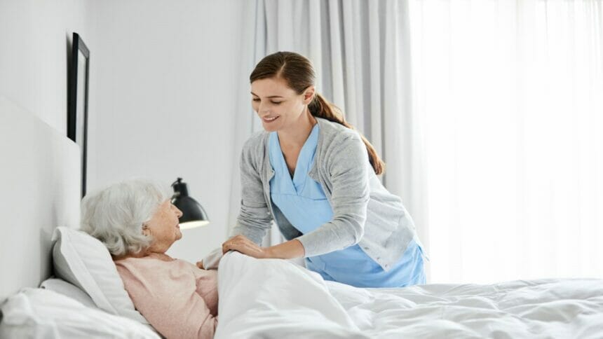 Caretaker tending to woman in her bed