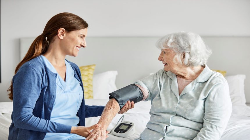 Caregiver checks woman's blood pressure at home