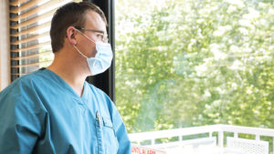 Healthcare worker wearing mask looks out the window
