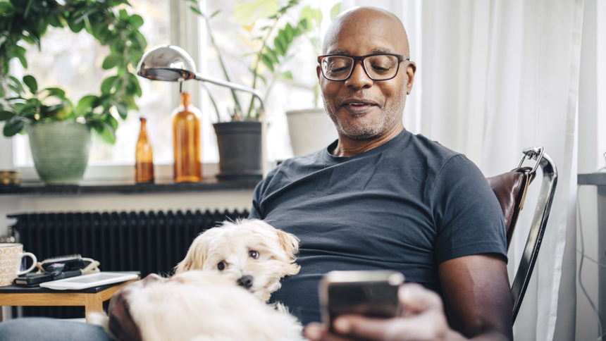 Man on cell phone with dog on lap