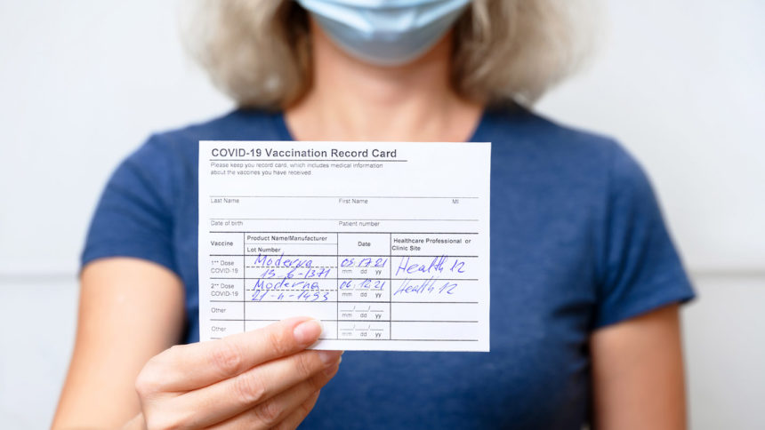 woman holding up COVID-19 vaccination card