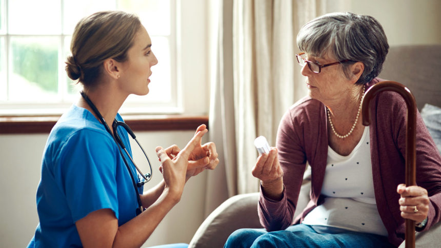 Caregiver instructing older woman about taking medication