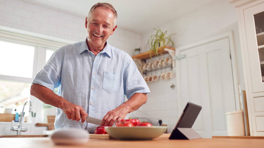 Man preparing meal using smart speaker.