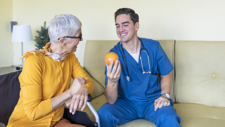 Healthcare worker giving older adult an orange