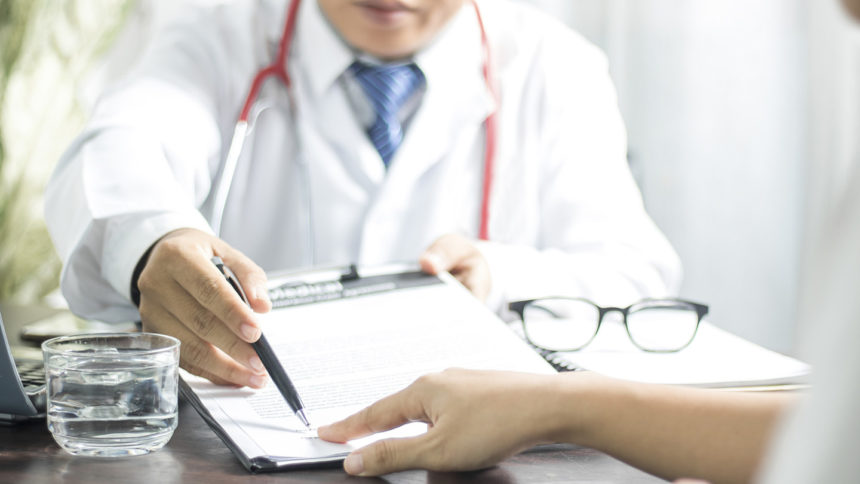 Doctor points to where patient should sign medical record.