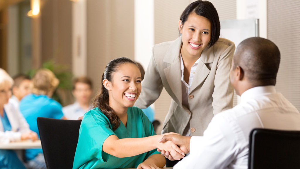 Member of long-term care workforce shaking hands during recruiting job interview.