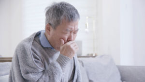 man covering his mouth while coughing