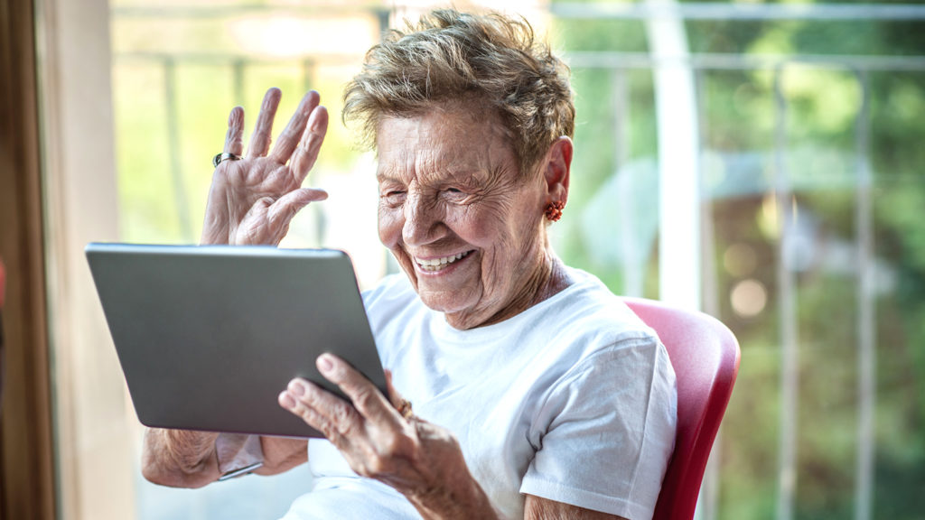 A very senior woman using digital tablet on apartment balcony