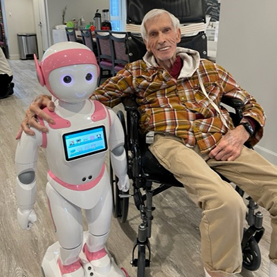 Older man in a wheelchair with his arm around a Solera Social bot