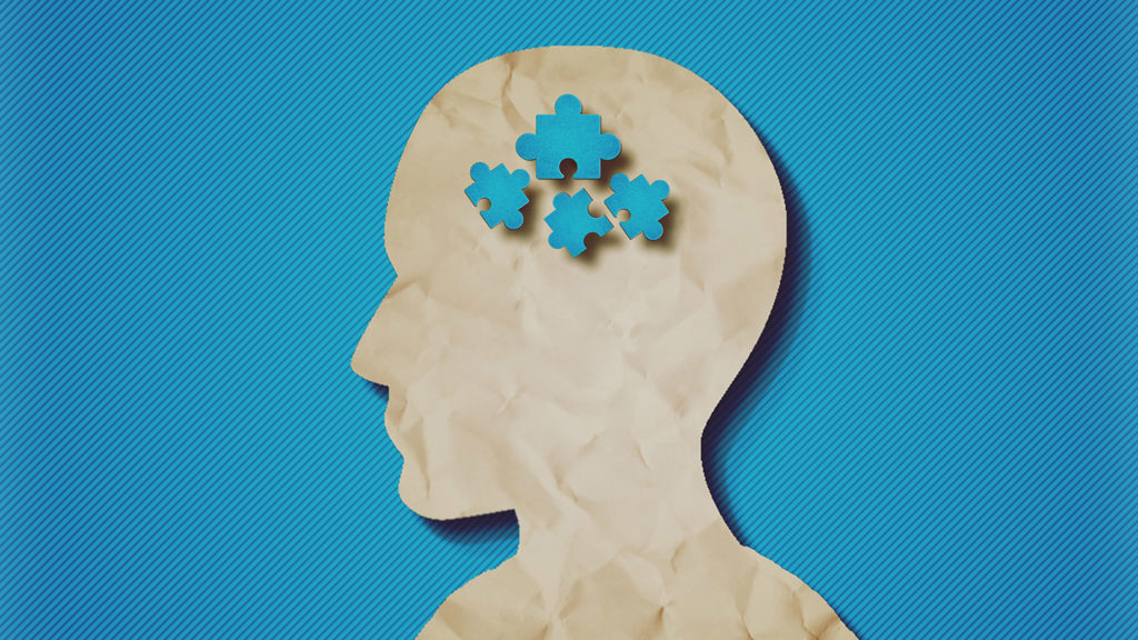 paper head with puzzle pieces-Autism concept.Blue background