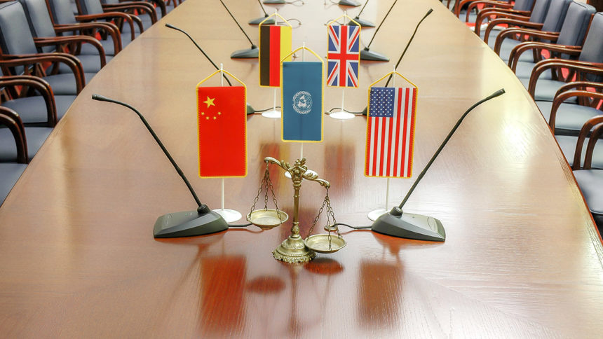 a decorative scale of justice at a conference table with international flags