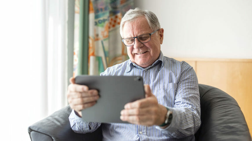 Senior man sitting at home using digital tablet for video calling. Mature man having online consultation with doctor.