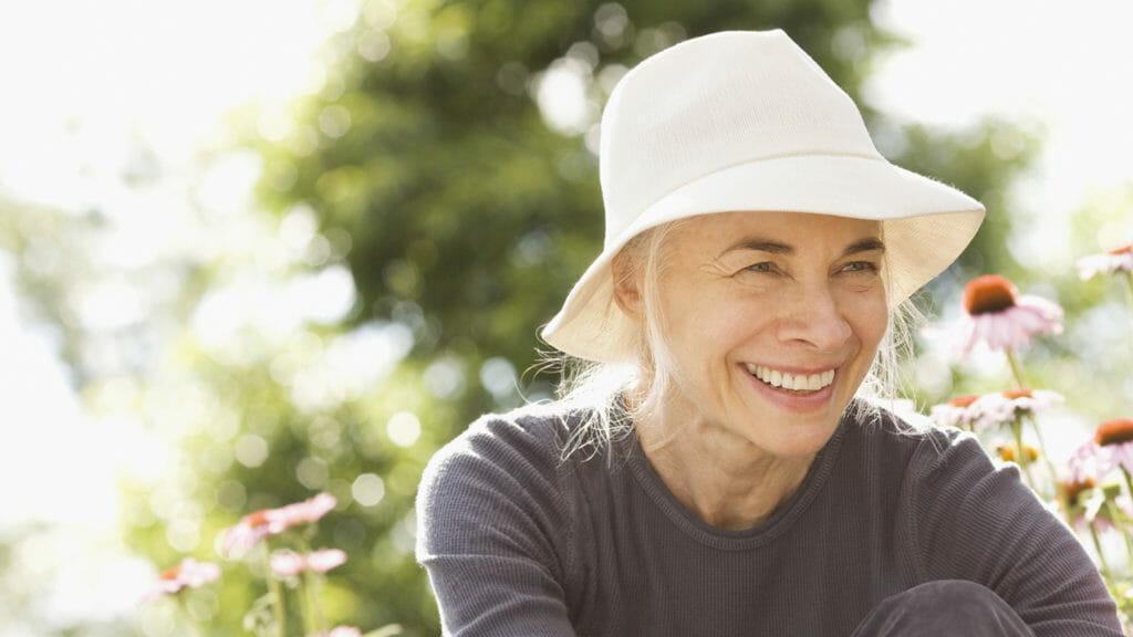 Smiling woman in hat in garden