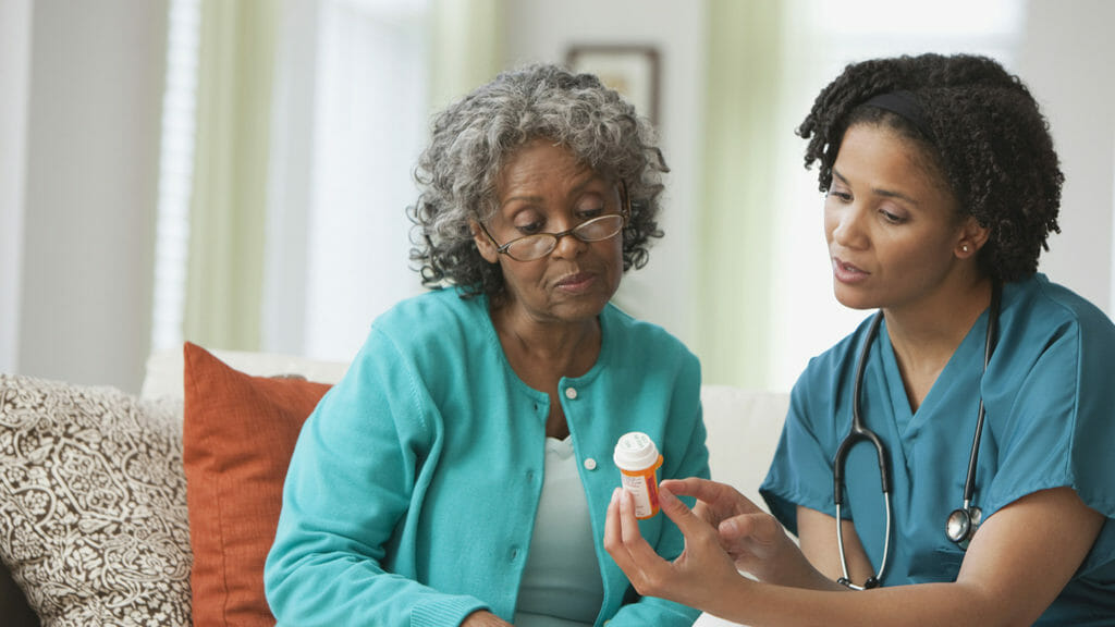 African home nurse reviewing prescription bottle with patient