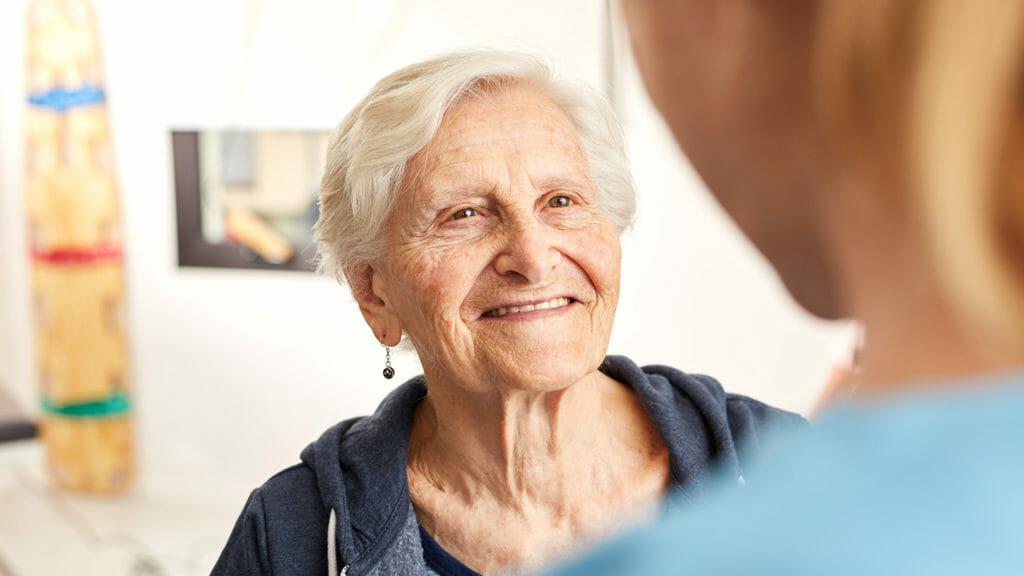 Satisfied senior woman in rehab together with physical therapist