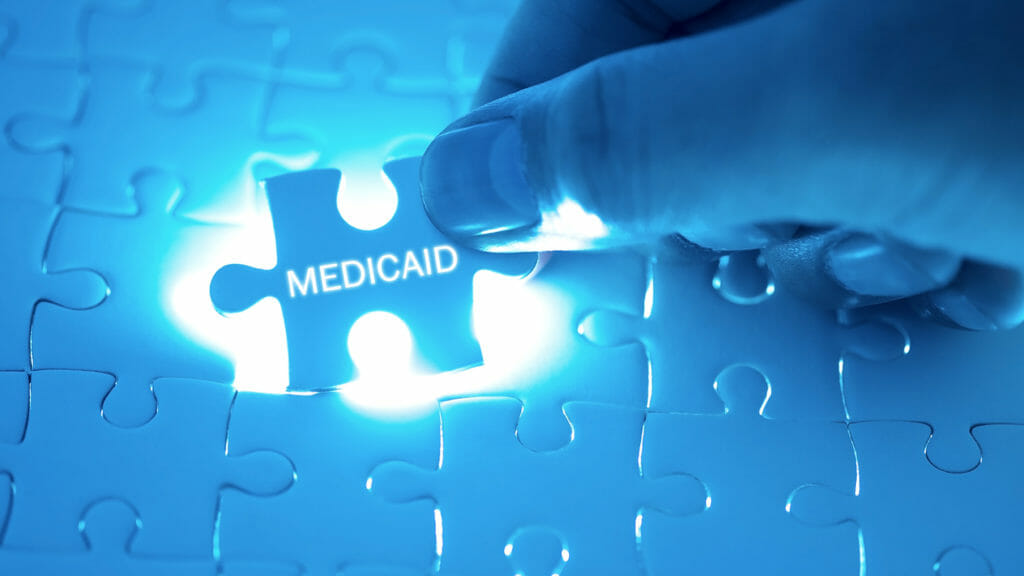 Health Care Concept. Doctor holding a jigsaw puzzle with MEDICAID word.