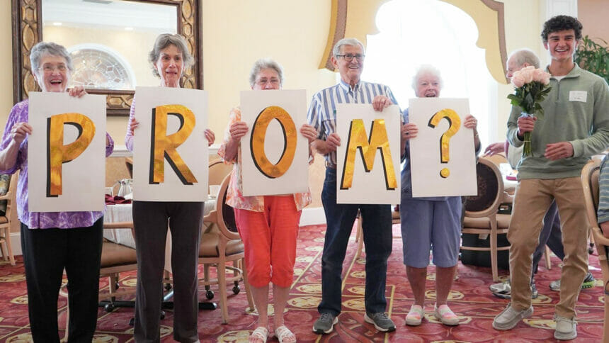 Older adults holding up signs that spell out prom