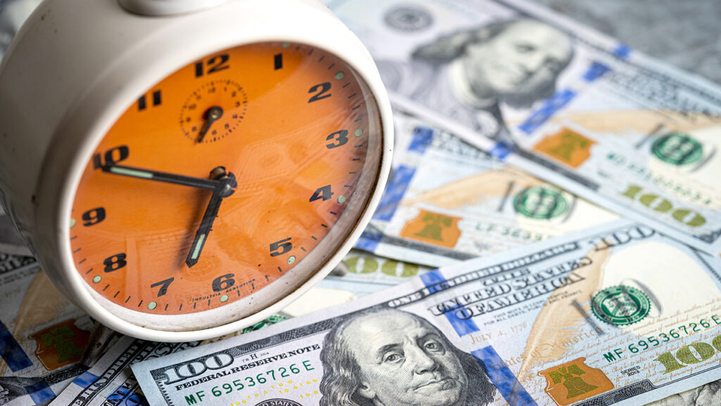 Orange clock over money