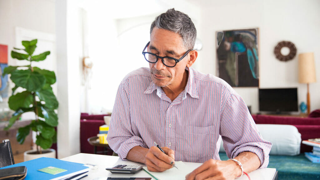 Mature man wearing eyeglasses working on personal finances at home