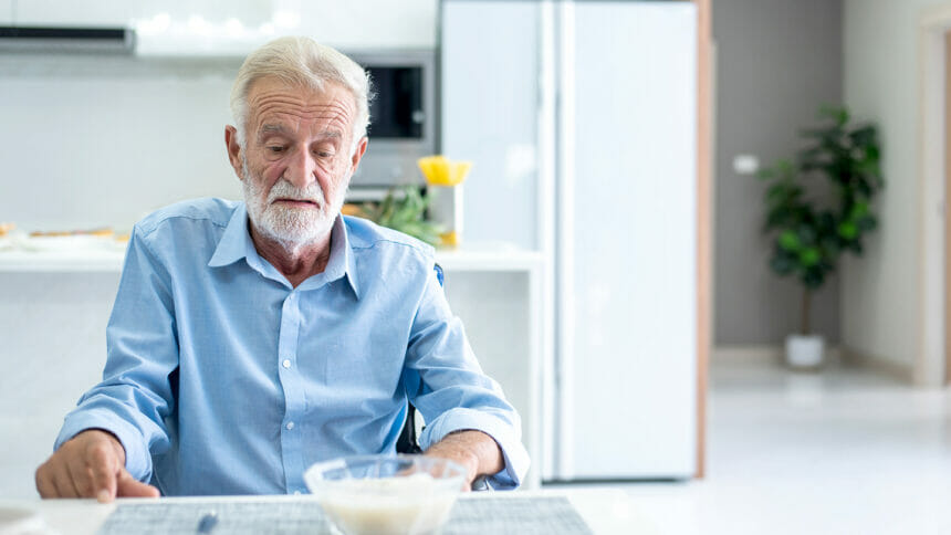 Elderly man looking down at a bowl of food