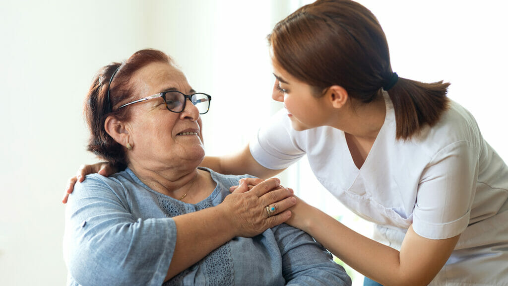 Caring nurse talks with her elderly patient