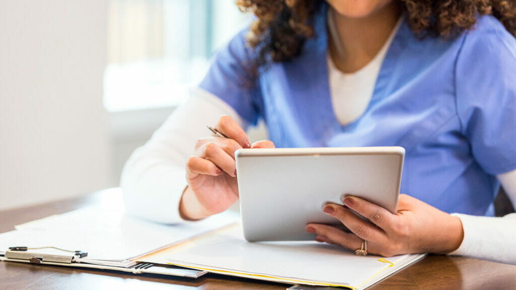 While working on a home healthcare case, a nurse uses a digital tablet add notes to a patient's electronic medical chart.
