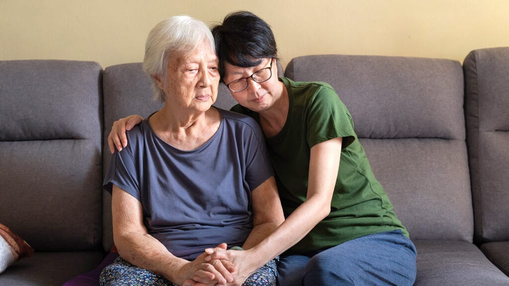 Mature Asian woman spending quality time with her depressed elderly mother at home.