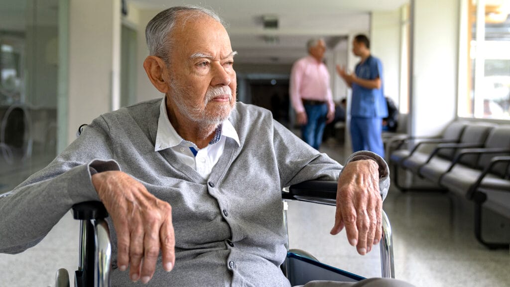 Disabled elderly man in a wheelchair at the hospital looking upset - healthcare and medicine