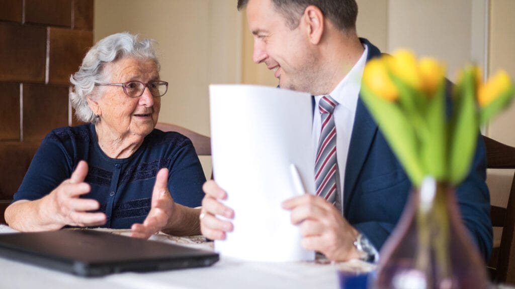 Happy lawyer looking at his satisfied elderly client when finishing up the paperwork