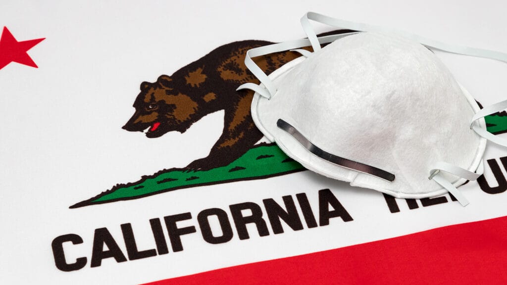 California state flag and N95 face mask. Concept of state and local government face covering mandate, order, requirement and social distancing during Covid-19 coronavirus pandemic