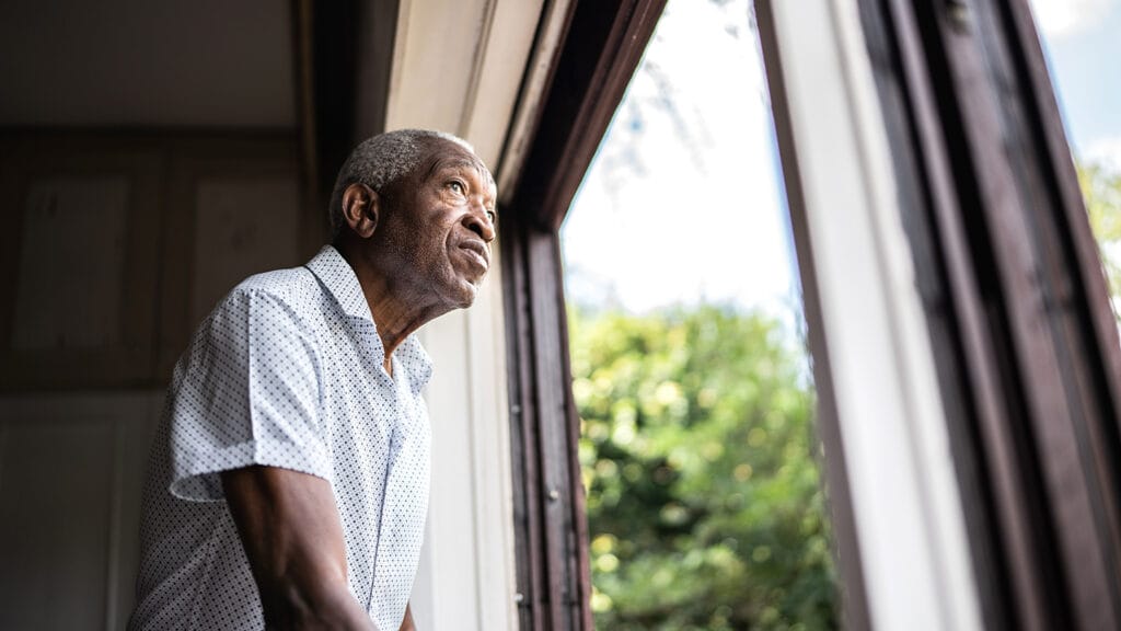 Older Black man looking out a window