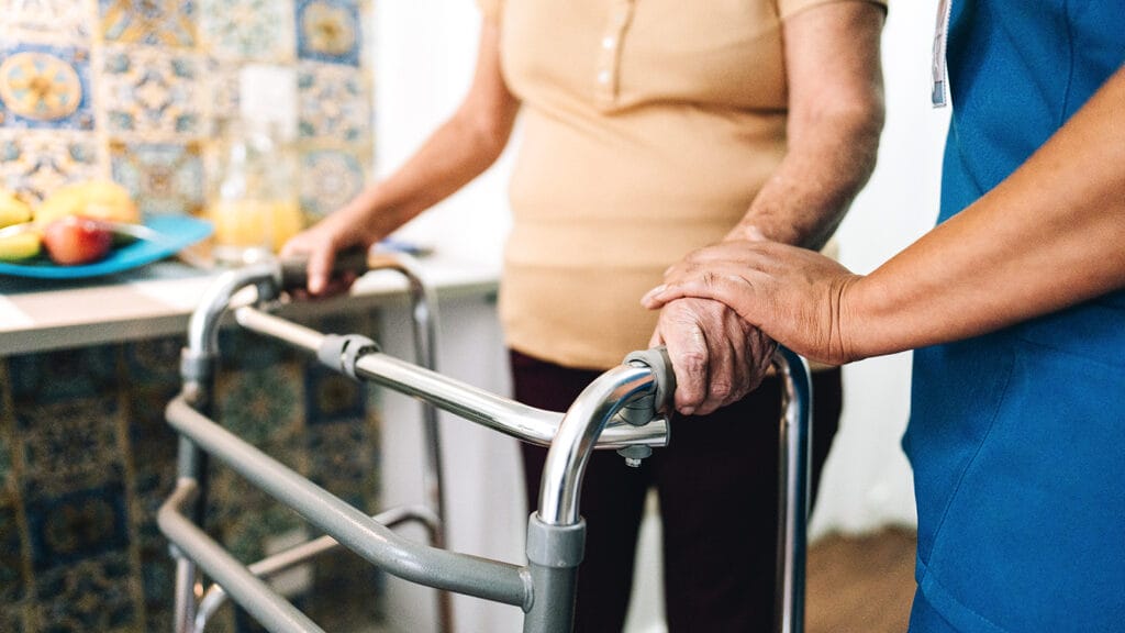 Home caregiver helping a senior woman walking at home